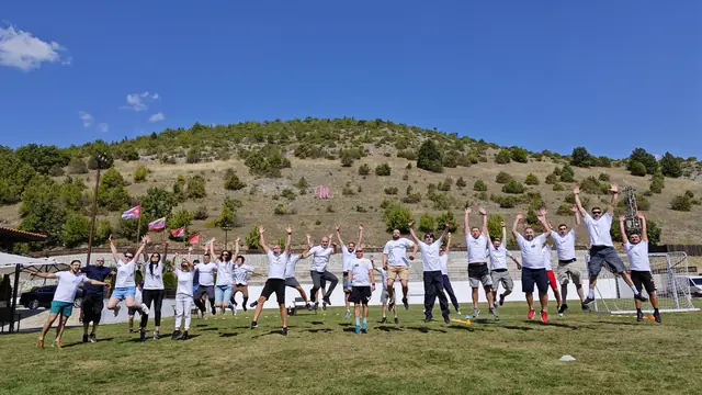 The eFellows team jumping in the air together on a grass field